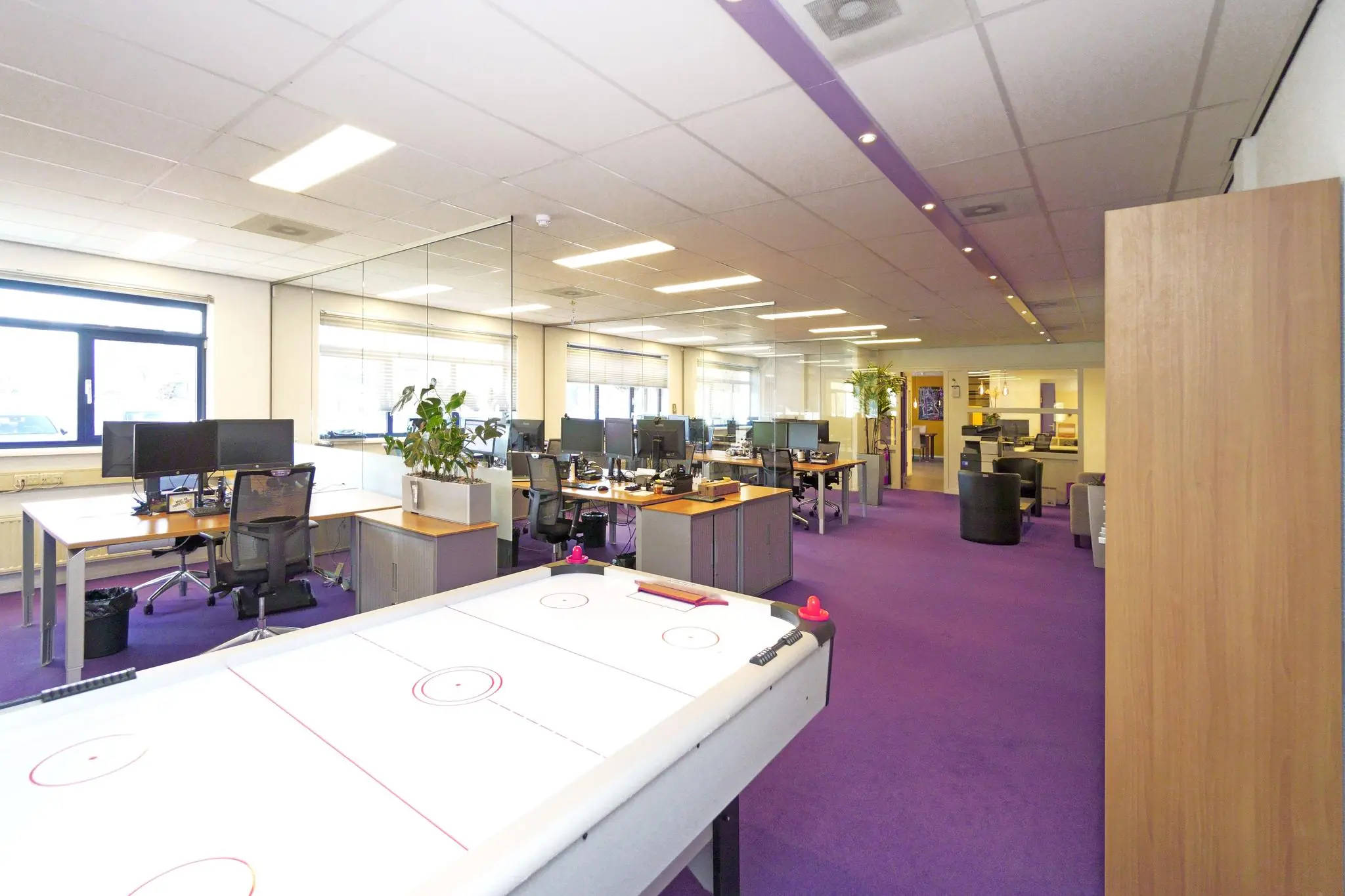 Modern kantoor aan de Zuiderweg met open werkplekken, paarse vloerbedekking en een airhockeytafel op de voorgrond.
