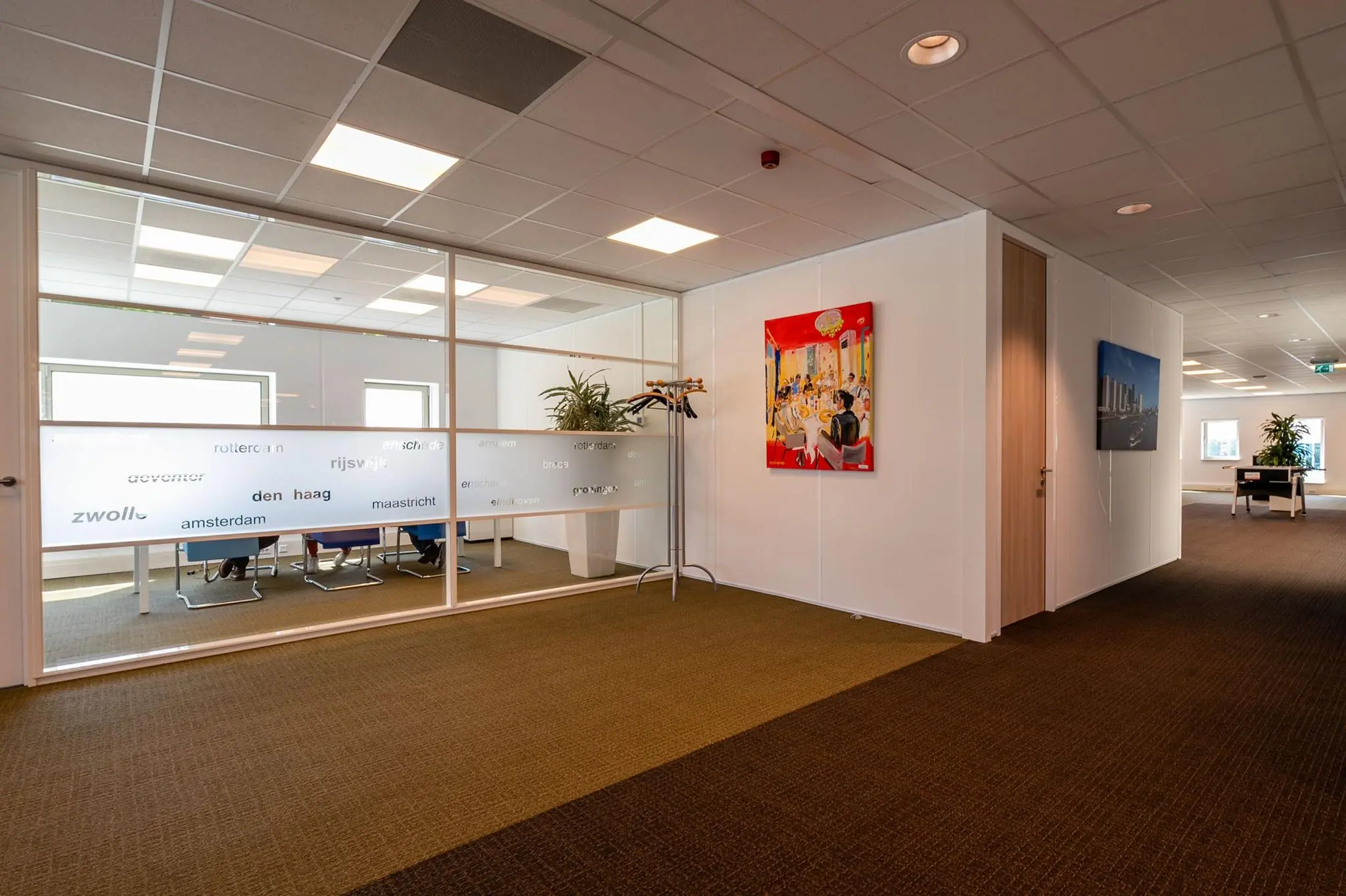 Moderne kantoorruimte aan de Bahialaan met vergaderruimte, kunst aan de muur en glazen panelen met stadsnamen.