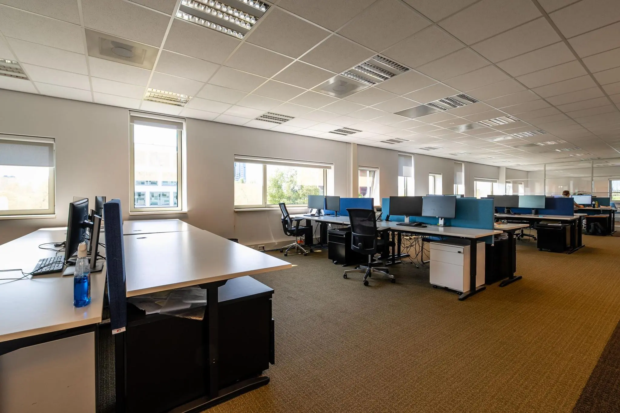 Moderne, ruime kantoortuin aan de Bahialaan met meerdere werkplekken en grote ramen.