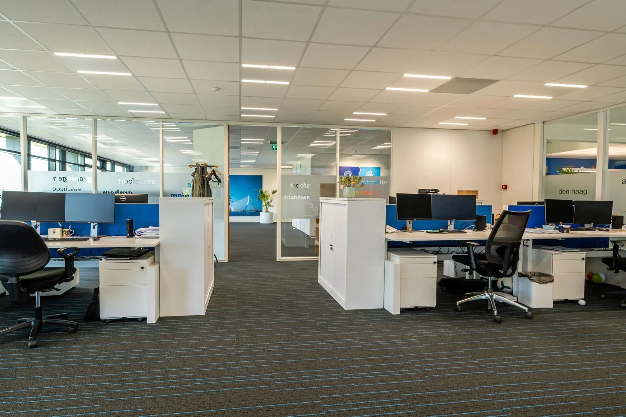 Moderne open kantoorruimte aan de Bahialaan met meerdere werkplekken en glazen wanden.