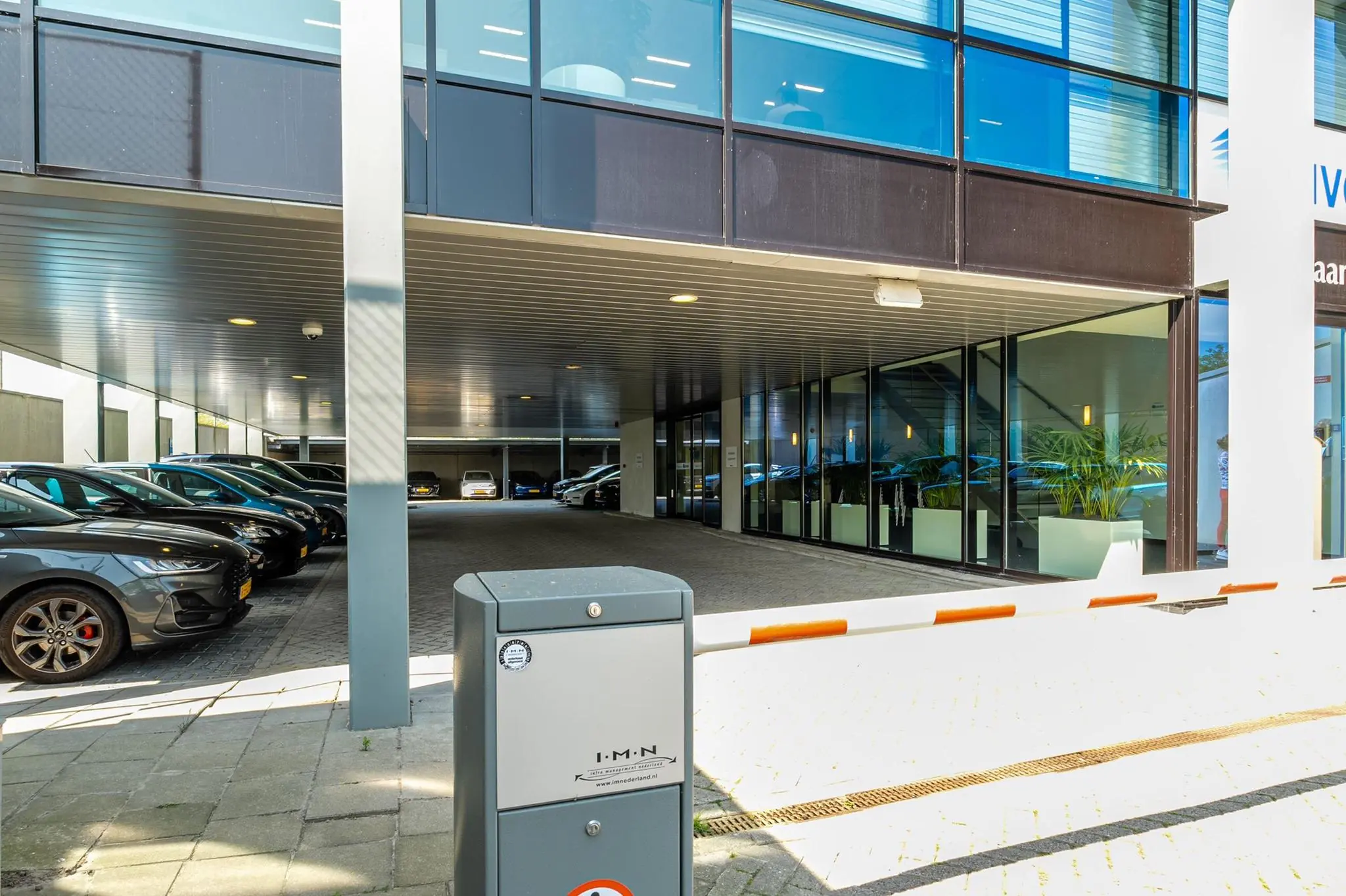 Overdekte parkeerplaats met slagboom en kantoorgebouw aan de Bahialaan.