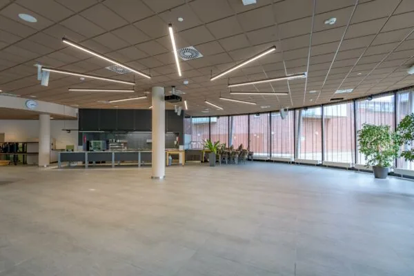 Ruime en moderne hal op het Enthovenplein met een koffiecounter, grote ramen en strakke plafondverlichting.