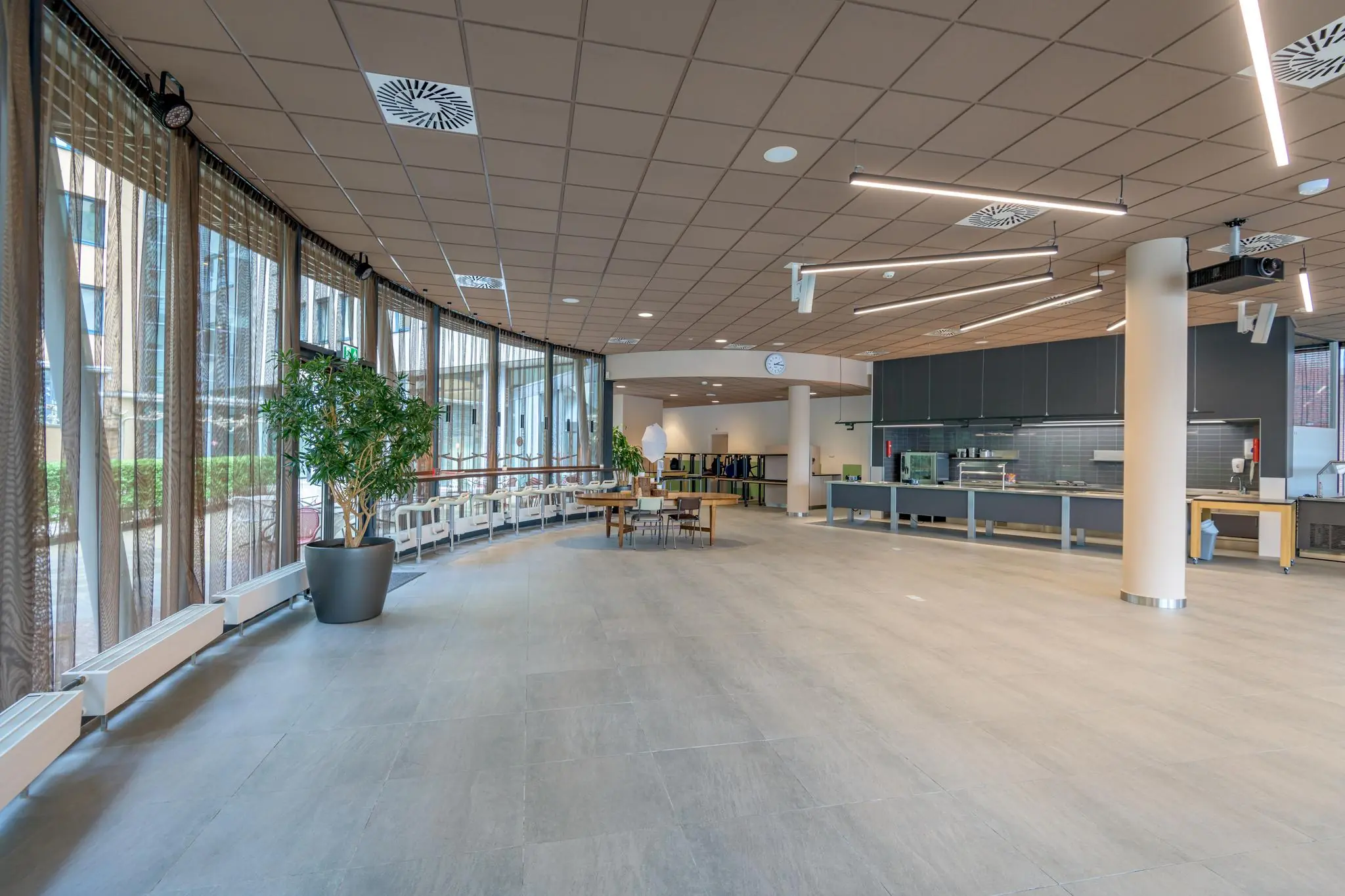 Ruim en modern ingericht atrium op het Enthovenplein met grote ramen, zitplaatsen en een lunchcounter.