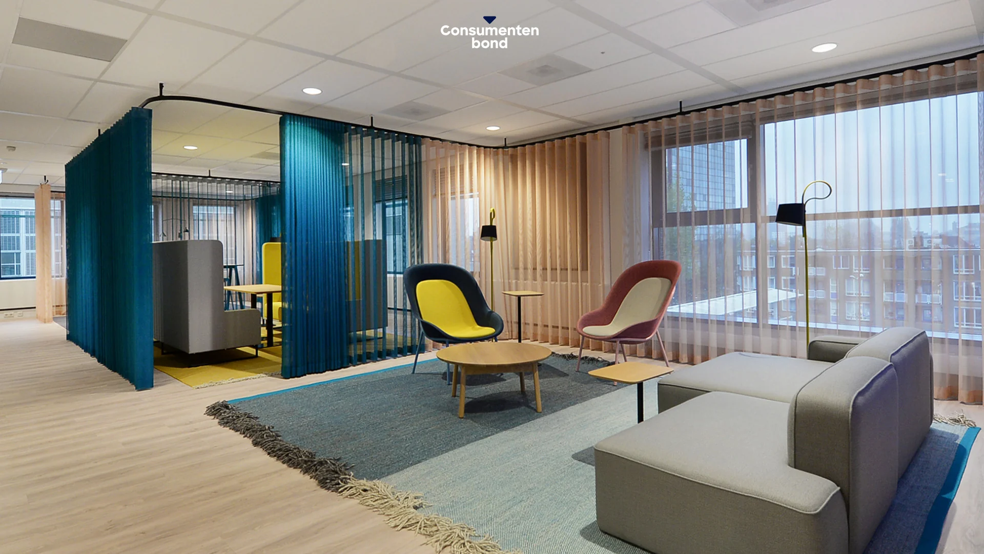Moderne lounge- en werkruimte op het Enthovenplein met kleurrijke meubels en transparante gordijnen.