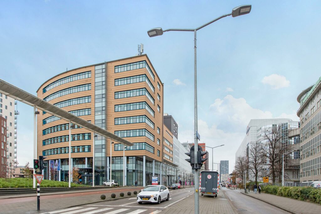 Straatbeeld van het Enthovenplein in Den Haag met moderne kantoorgebouwen en verkeer op de voorgrond.