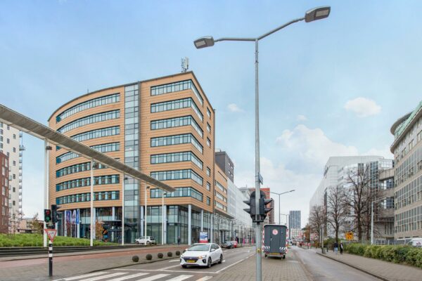 Straatbeeld van het Enthovenplein in Den Haag met moderne kantoorgebouwen en verkeer op de voorgrond.