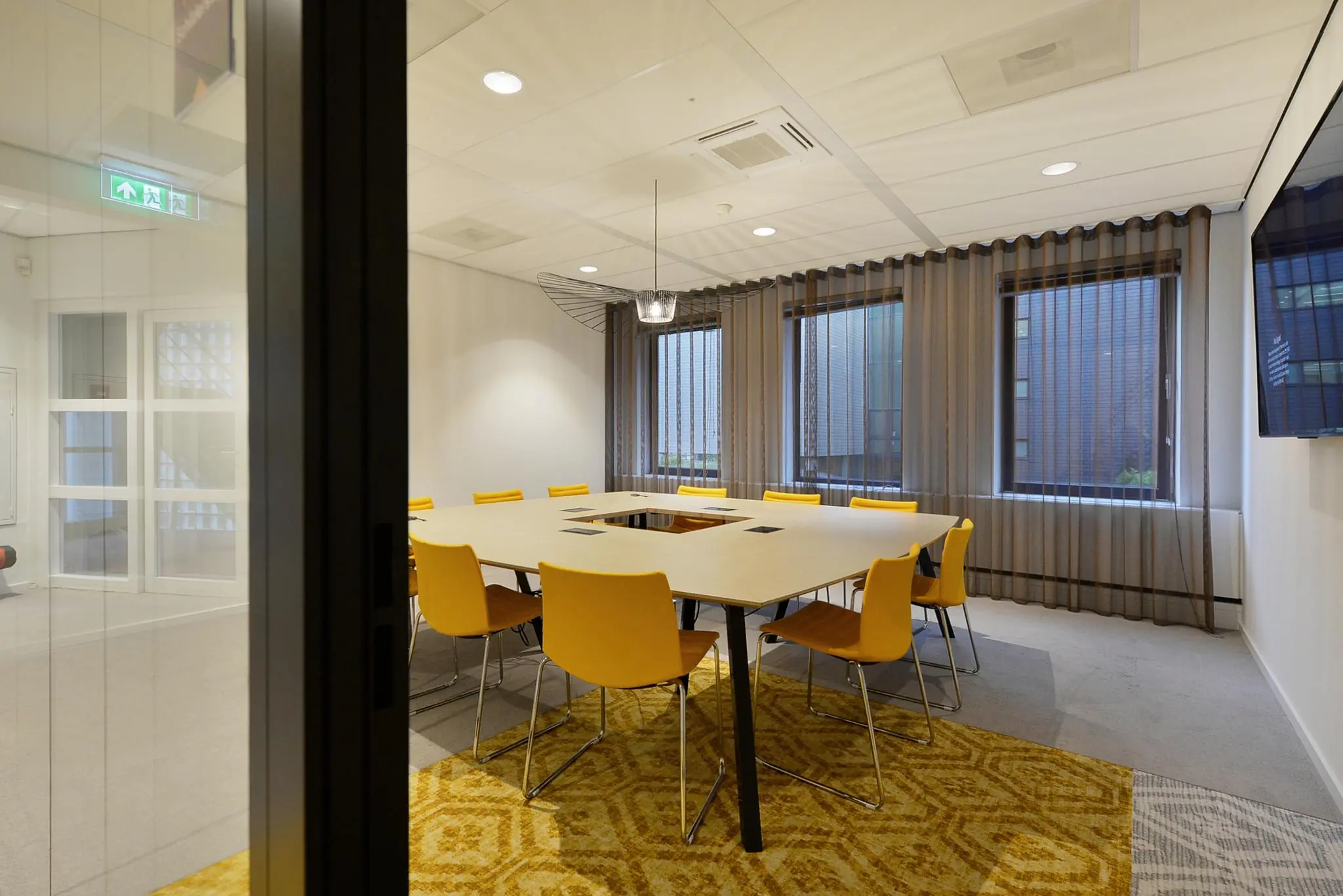 Vergaderruimte aan het Enthovenplein met gele stoelen en een vierkante tafelopstelling.