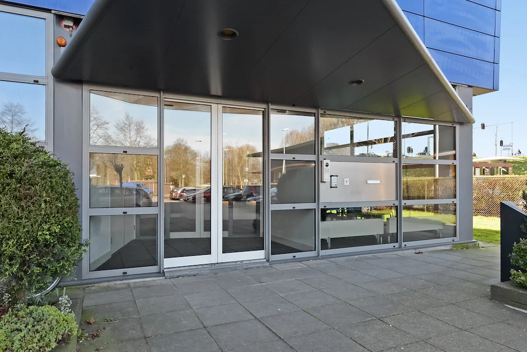 Entree van een modern kantoorgebouw aan de Kleveringweg met glazen deuren en overkapping.