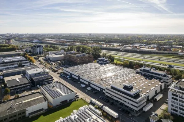 Luchtfoto van het bedrijventerrein Zonnebaan in Utrecht met magazijnen, kantoren en zonnepanelen op de daken, gelegen naast de snelweg.
