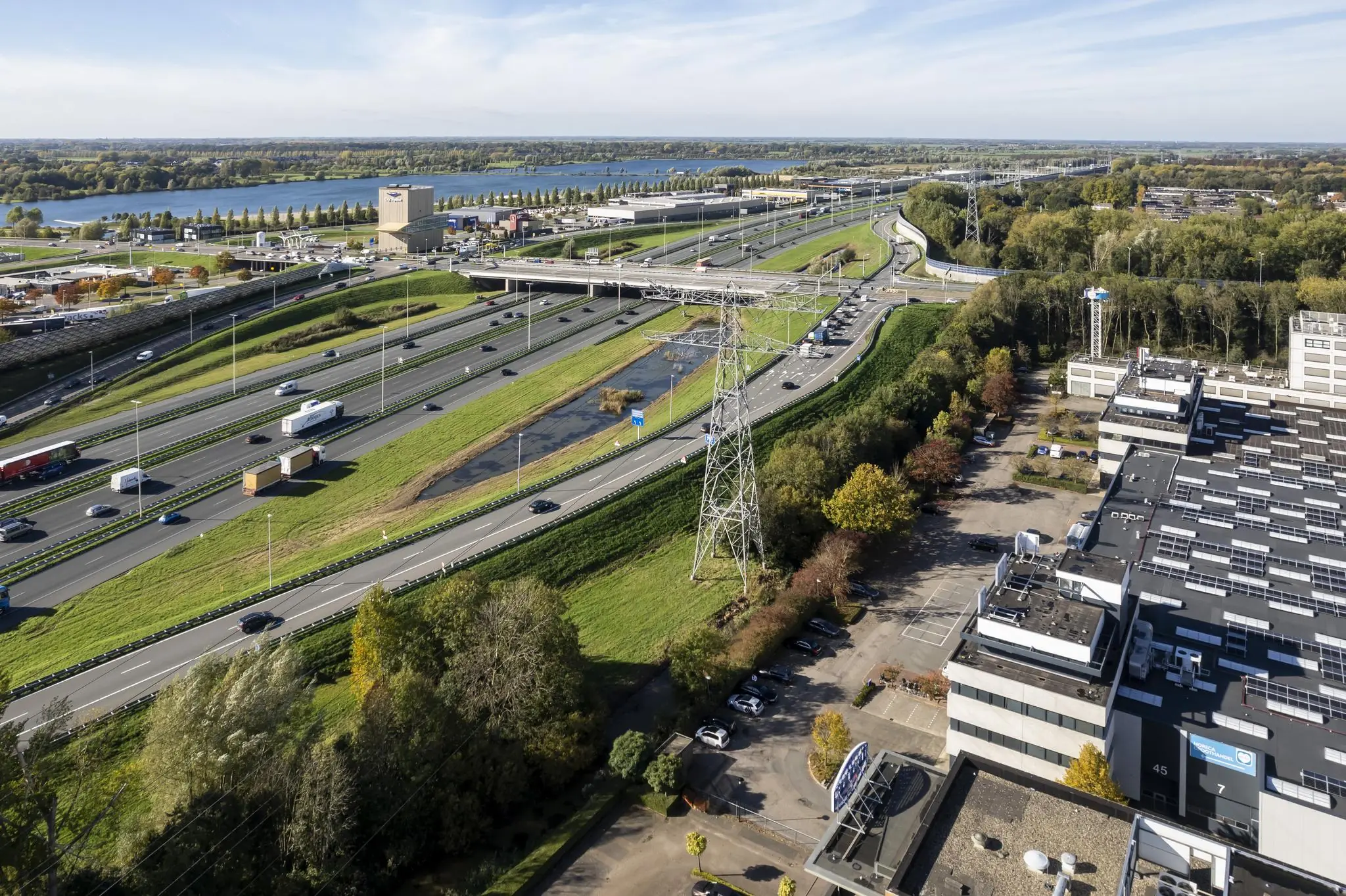 Luchtfoto van bedrijventerrein De Wetering nabij de Zonnebaan in Utrecht, met snelwegen, kantoorgebouwen en water op de achtergrond.