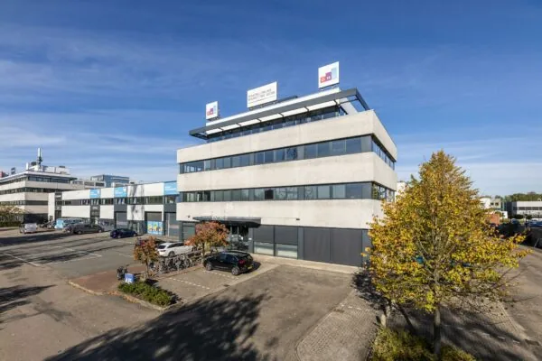 Kantoorgebouw aan de Zonnebaan 45 in Utrecht met het logo van OMG op het dak en een parkeerplaats op de voorgrond.