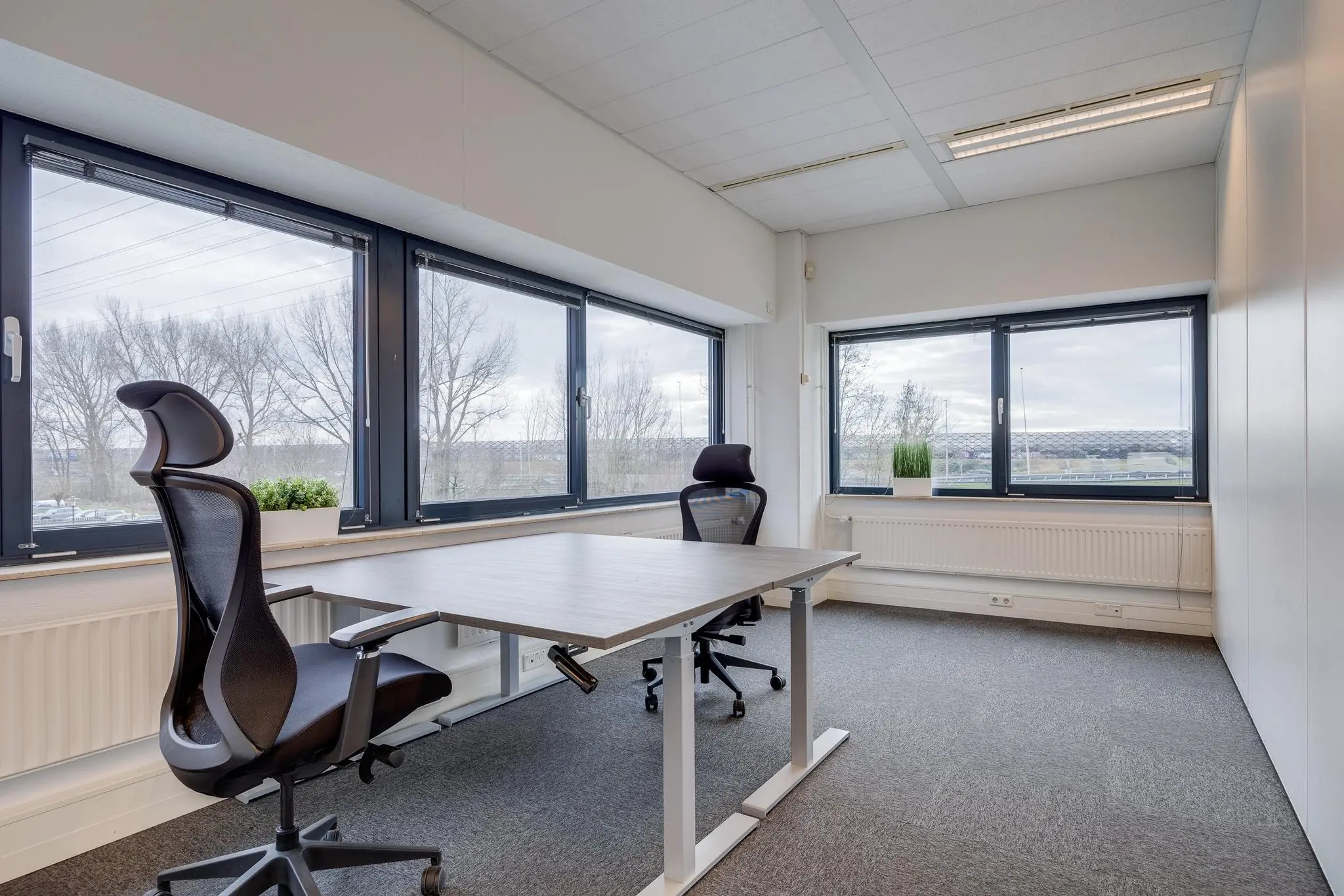 Licht en modern kantoor met twee bureaustoelen en grote ramen aan de Zonnebaan.