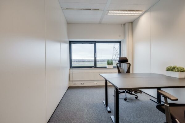 Modern, licht kantoor aan de Zonnebaan met twee bureaus, bureaustoelen en uitzicht op een open veld.