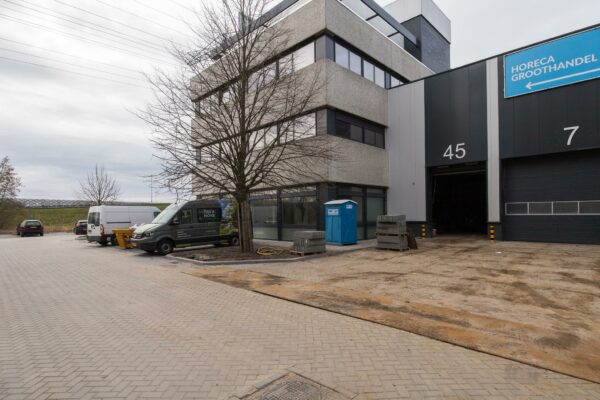 Bedrijventerrein aan de Zonnebaan met een modern kantoorgebouw, geparkeerde bestelwagens en een ingang naar loodsnummer 45.