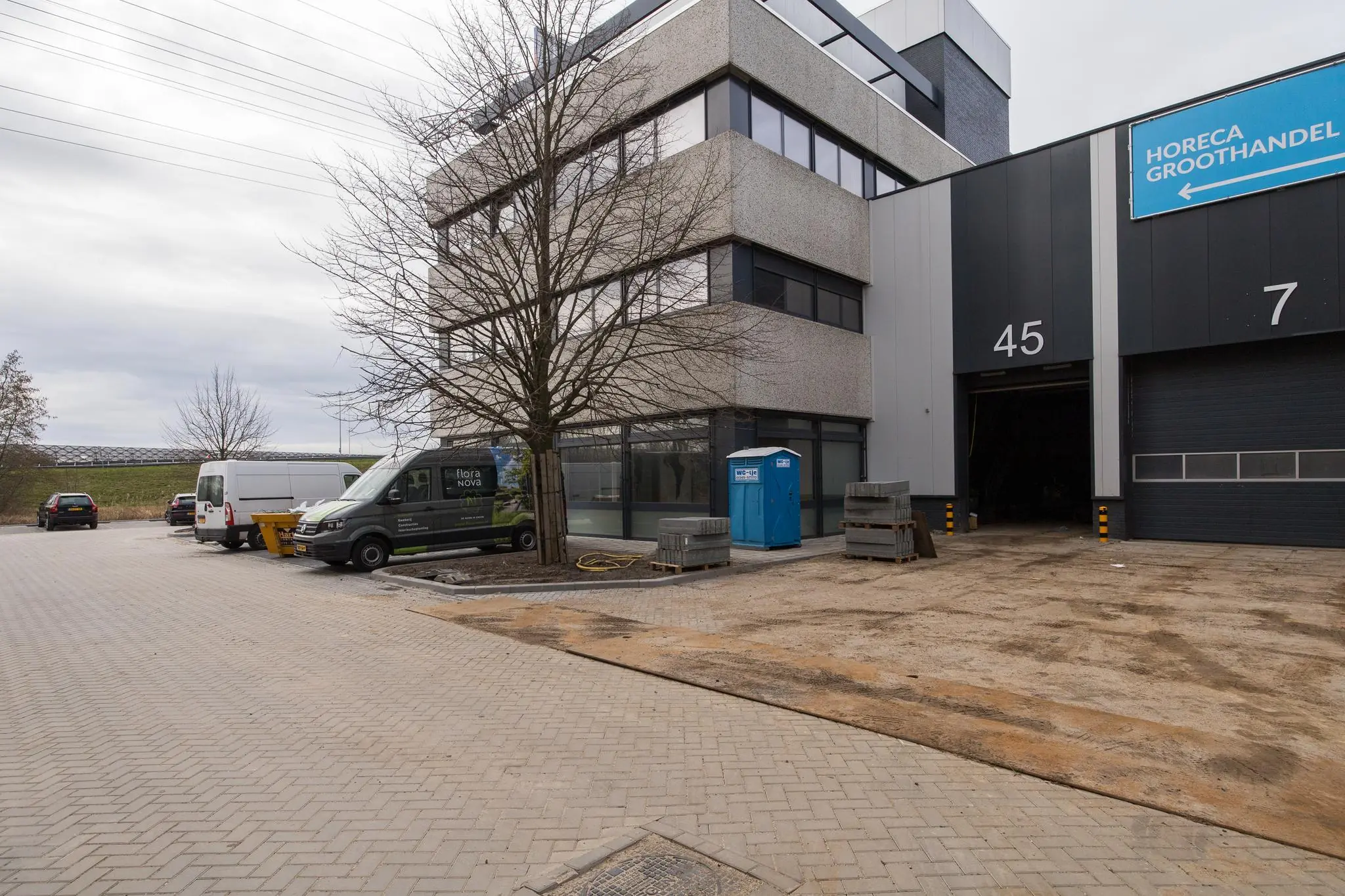 Bedrijventerrein aan de Zonnebaan met een modern kantoorgebouw, geparkeerde bestelwagens en een ingang naar loodsnummer 45.