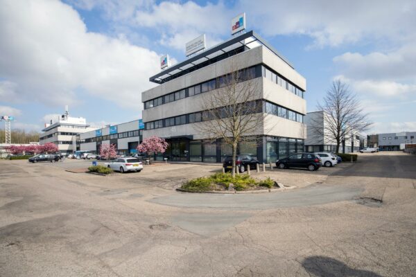 Kantoorgebouw aan de Zonnebaan 45 in Utrecht met parkeerplaatsen en bloeiende bomen op de voorgrond.