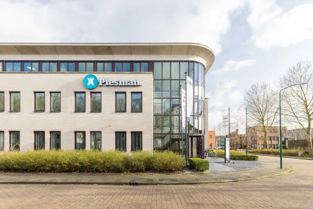 Modern kantoorgebouw aan de Plesmanstraat met het logo van Plesman op de gevel en fietsen geparkeerd bij de ingang.