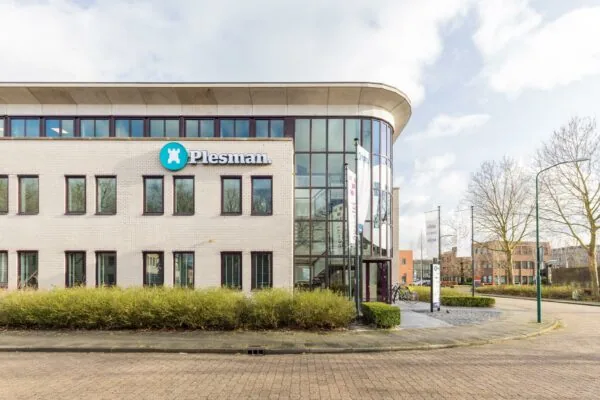Modern kantoorgebouw aan de Plesmanstraat met het logo van Plesman op de gevel en fietsen geparkeerd bij de ingang.