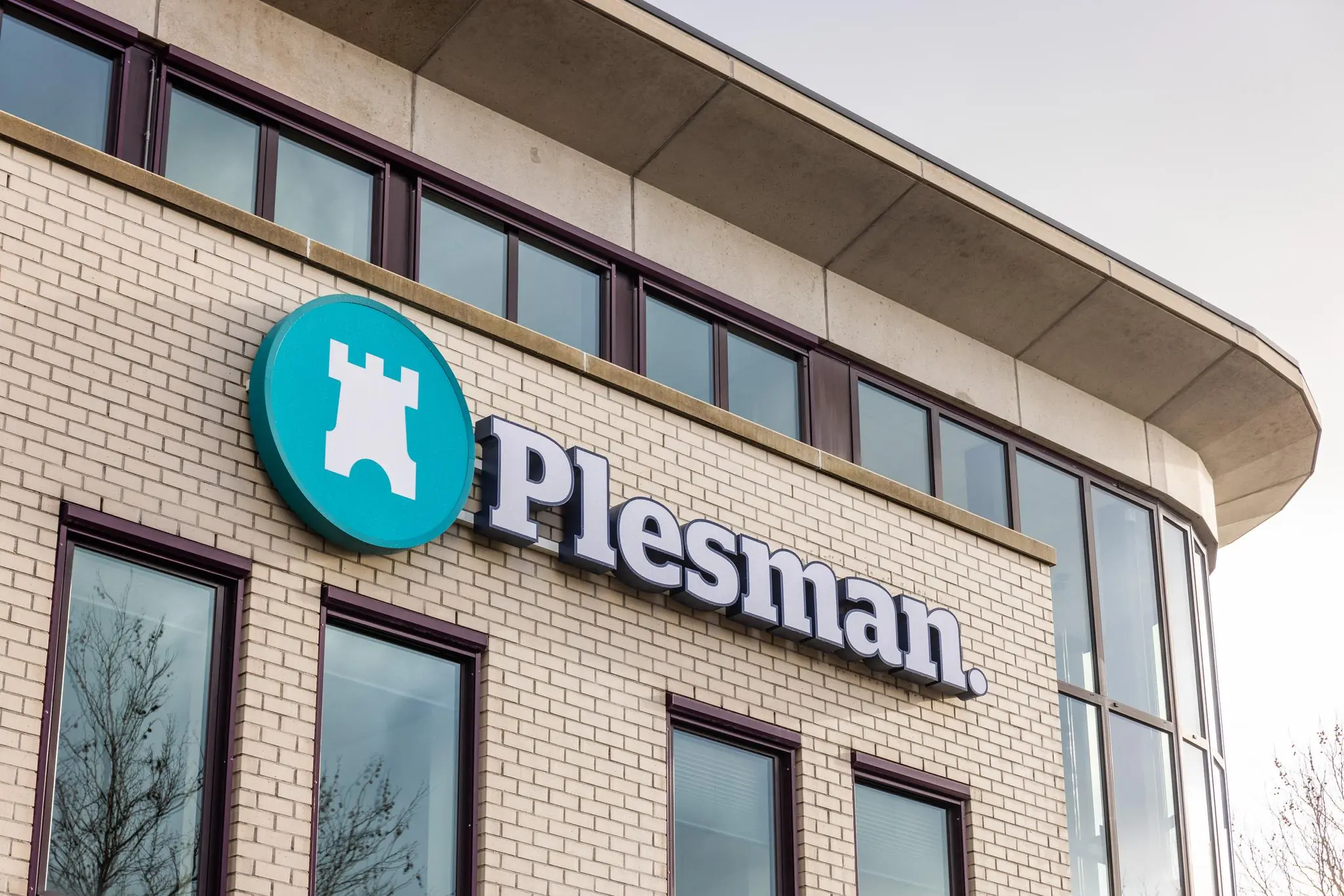 Gevel van een modern kantoorgebouw met het logo en de naam 'Plesman' op de Plesmanstraat.