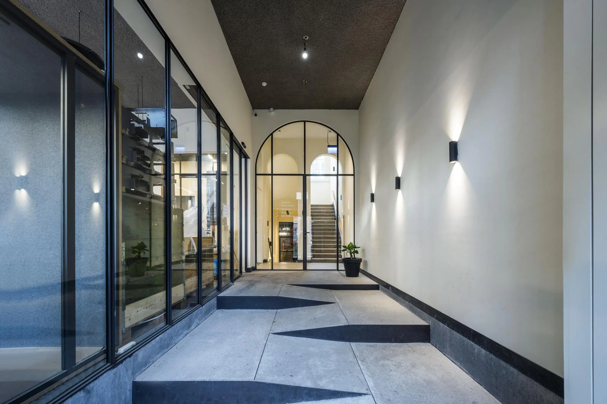 Moderne entree van een gebouw aan de Overtoom met glazen pui, sfeerverlichting en strakke betonnen vloer.