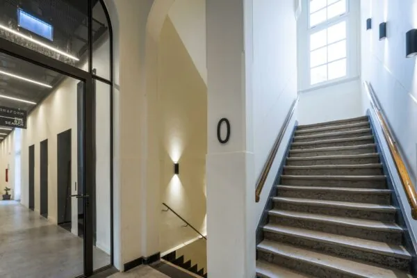 Trapopgang en gang in een modern kantoorpand aan de Overtoom met strak afgewerkte muren en grote ramen.