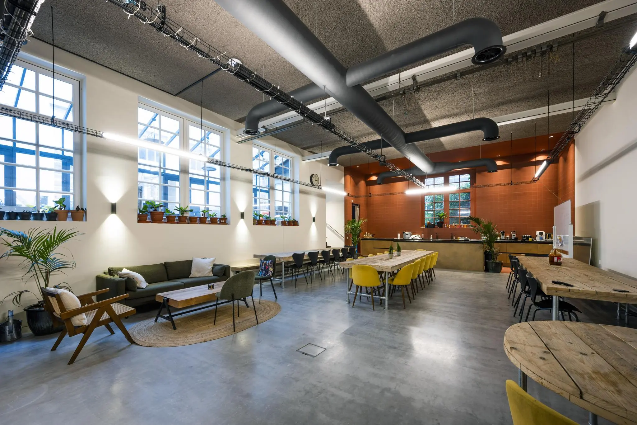 Moderne, sfeervol ingerichte gemeenschappelijke ruimte aan de Overtoom met zithoeken, lange eettafels en open keuken.