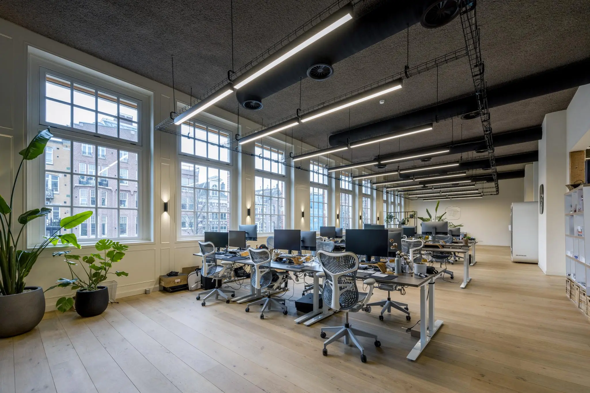Modern en licht kantoorinterieur aan de Overtoom met open werkplekken, grote ramen en designbureaustoelen.