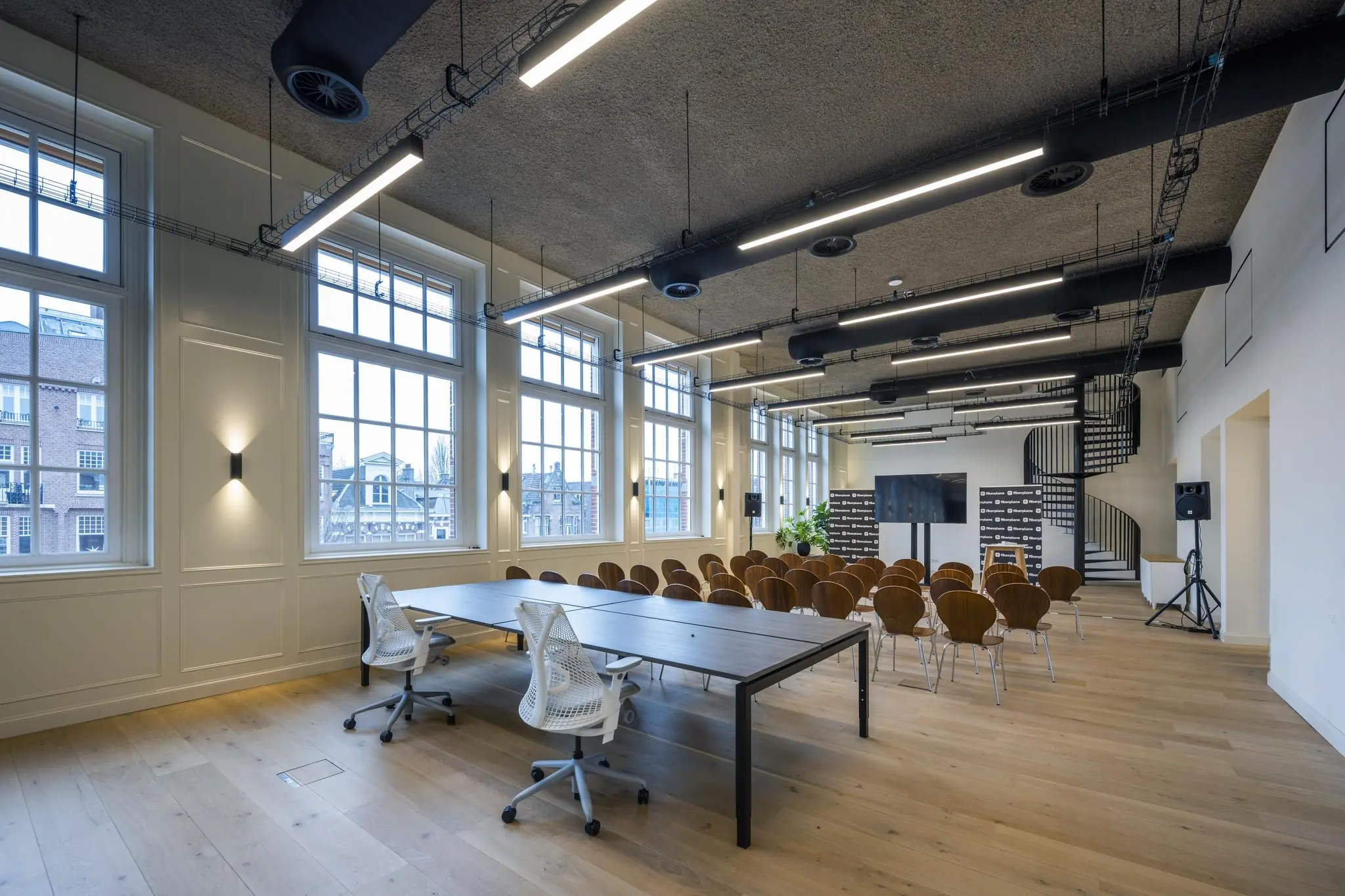 Moderne conferentieruimte aan de Overtoom met opgestelde stoelen, presentatiescherm en grote ramen met uitzicht op de stad.