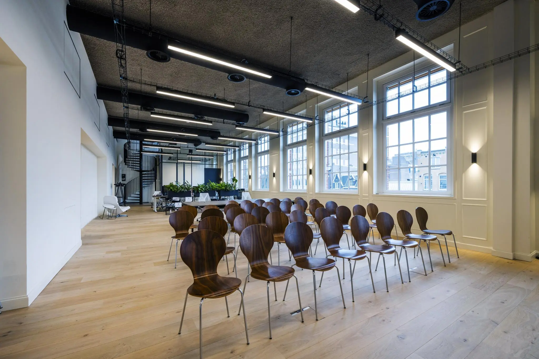 Moderne vergaderruimte aan de Overtoom met houten stoelen in opstelling en grote ramen die uitzicht bieden op de stad.