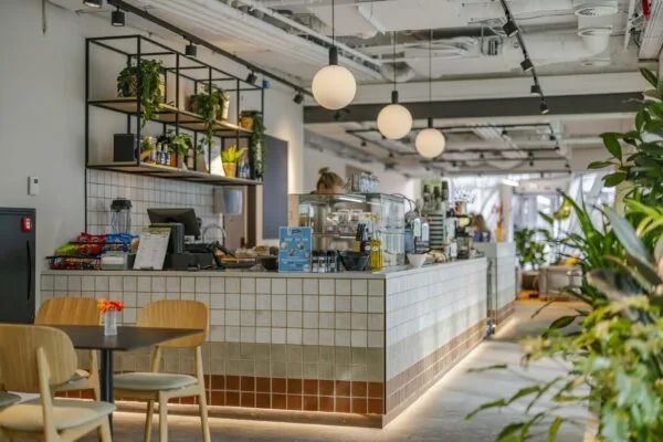 Moderne en sfeervol ingerichte koffiebar aan de Schenkkade met tegelcounter, hanglampen en veel planten.