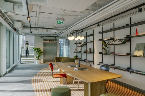 Moderne kantoorruimte aan de Schenkkade met houten vergadertafel, open boekenplanken en sfeervolle verlichting.