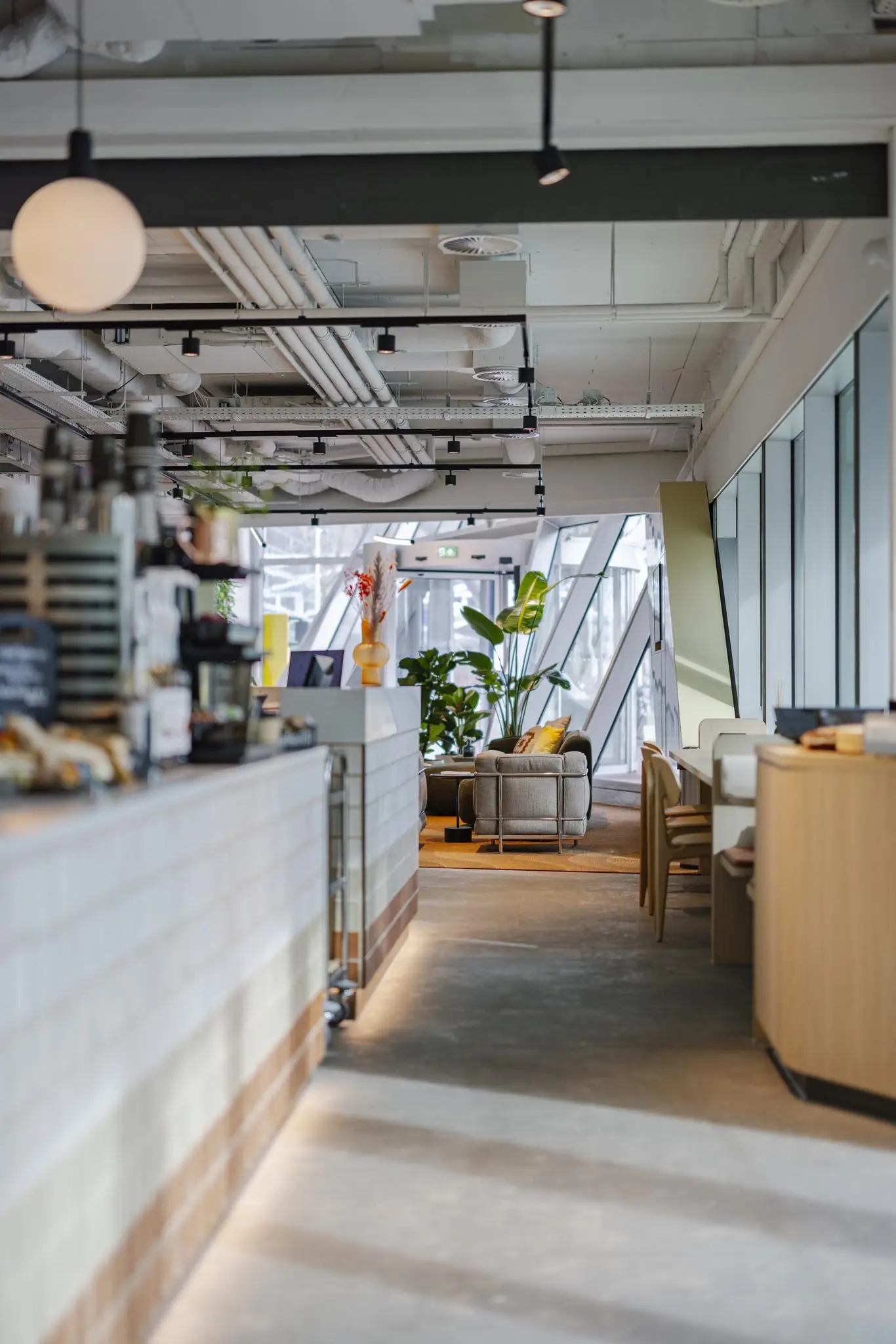 Modern interieur van een koffiebar of lobby aan de Schenkkade met zitgedeelte, planten en veel daglicht.