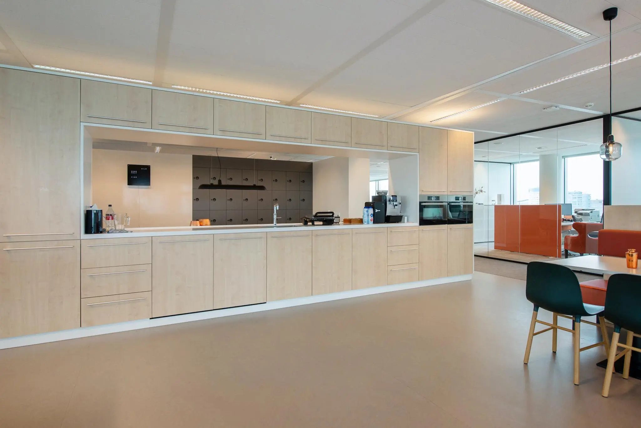 Moderne bedrijfskeuken met houtkleurige kasten en ingebouwde apparatuur aan de Schenkkade.
