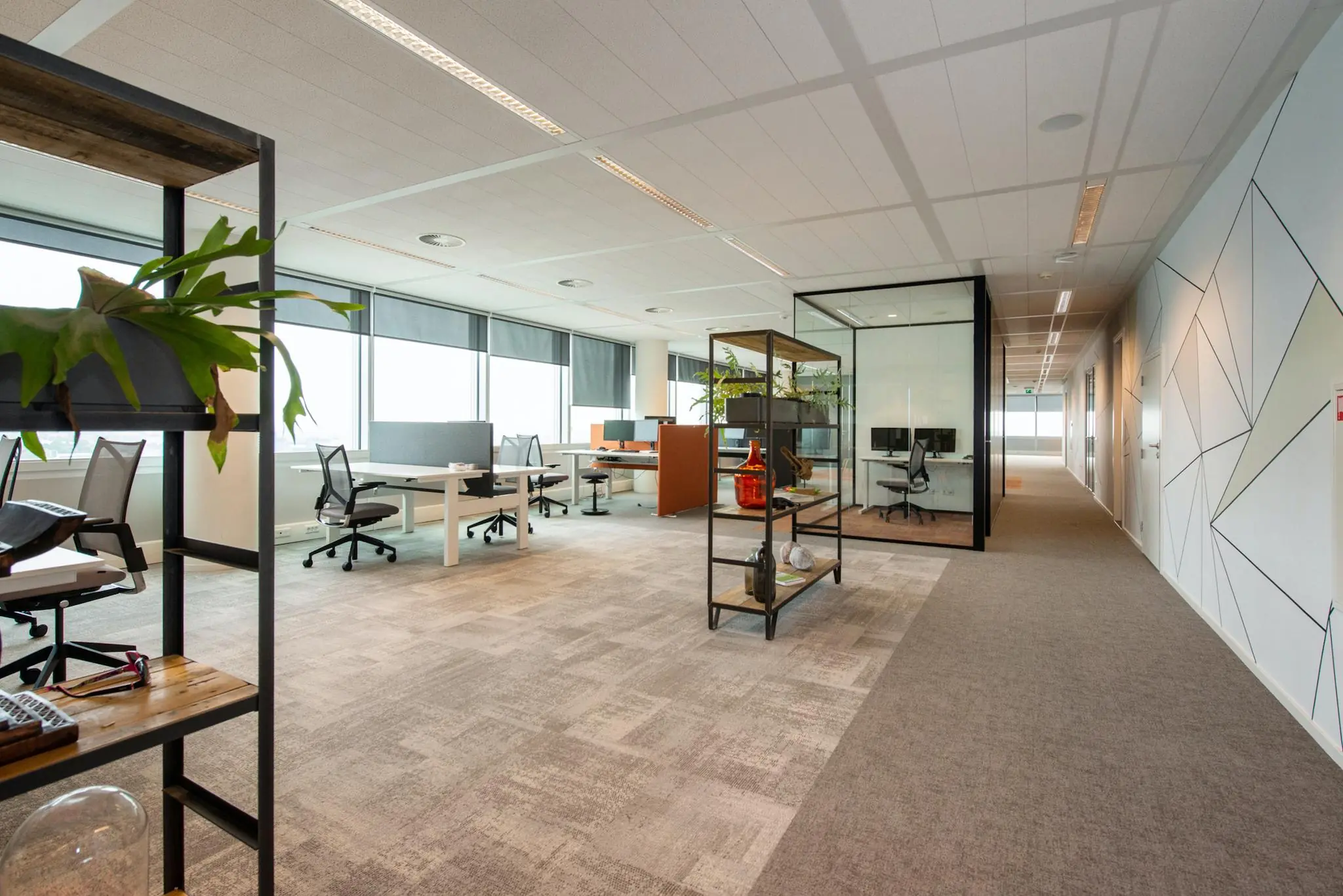 Modern en licht open kantoorinterieur aan de Schenkkade met werkplekken, glazen vergaderruimte en decoratieve elementen.