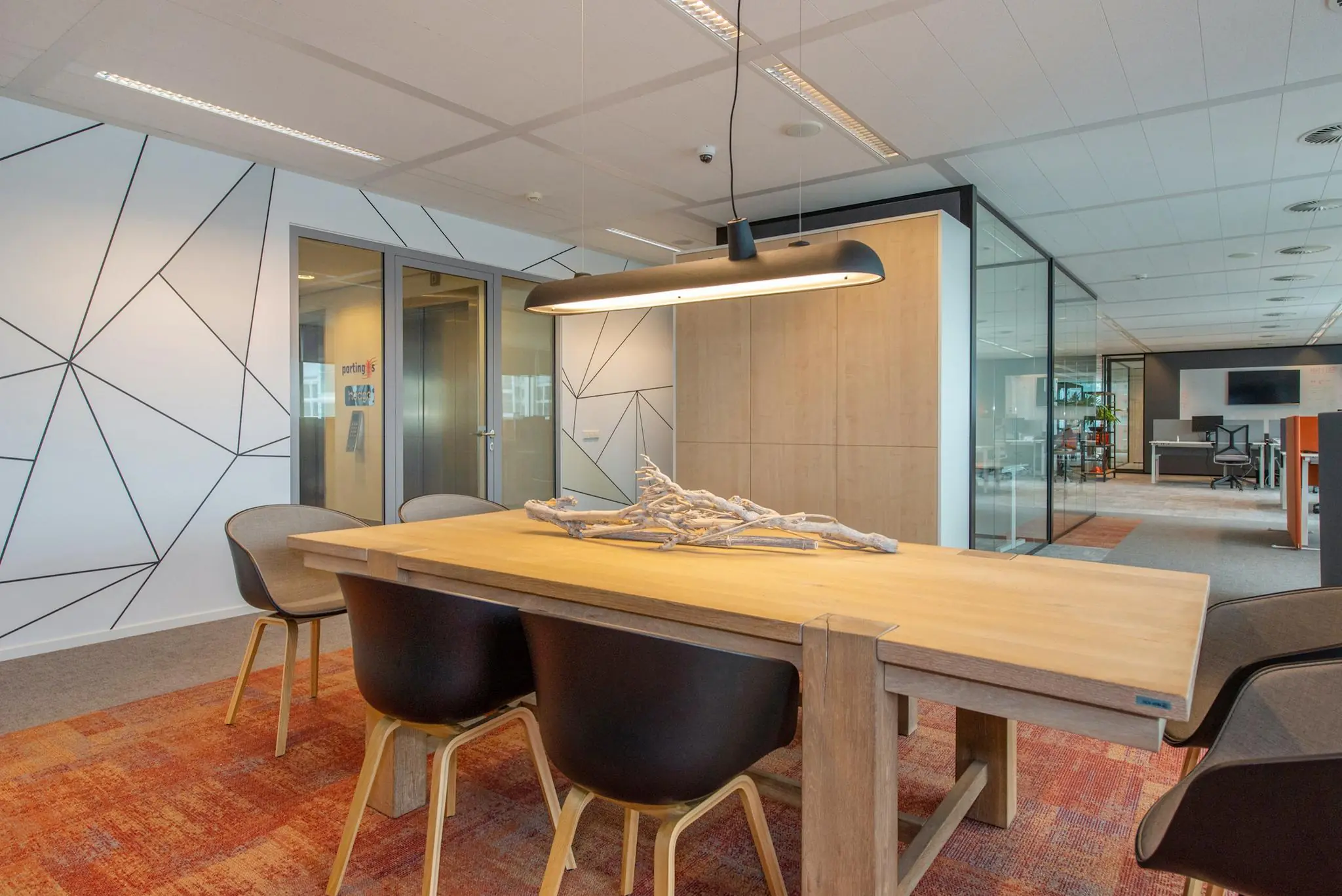 Moderne vergaderruimte aan de Schenkkade met houten tafel, designstoelen, decoratief lichtarmatuur en glaswanden.