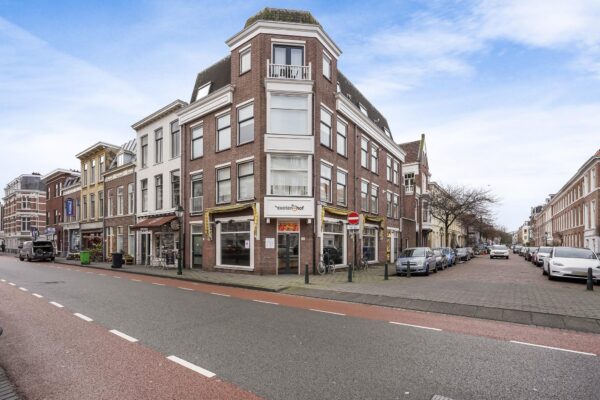 Hoekpand aan de Bankastraat met op de begane grond winkelruimte van "Exotenhof" en omliggende geparkeerde auto's.