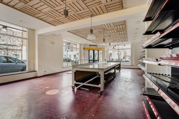 Leegstaand winkelpand aan de Bankastraat met metalen werktafel, legplanken en grote etalageramen.