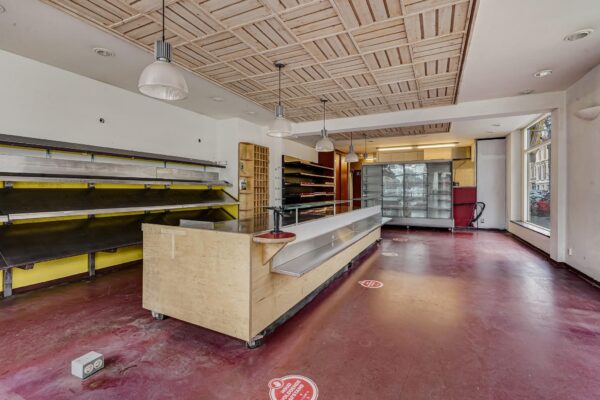Leegstaand winkelinterieur aan de Bankastraat met toonbank, schappen en koelvitrine.
