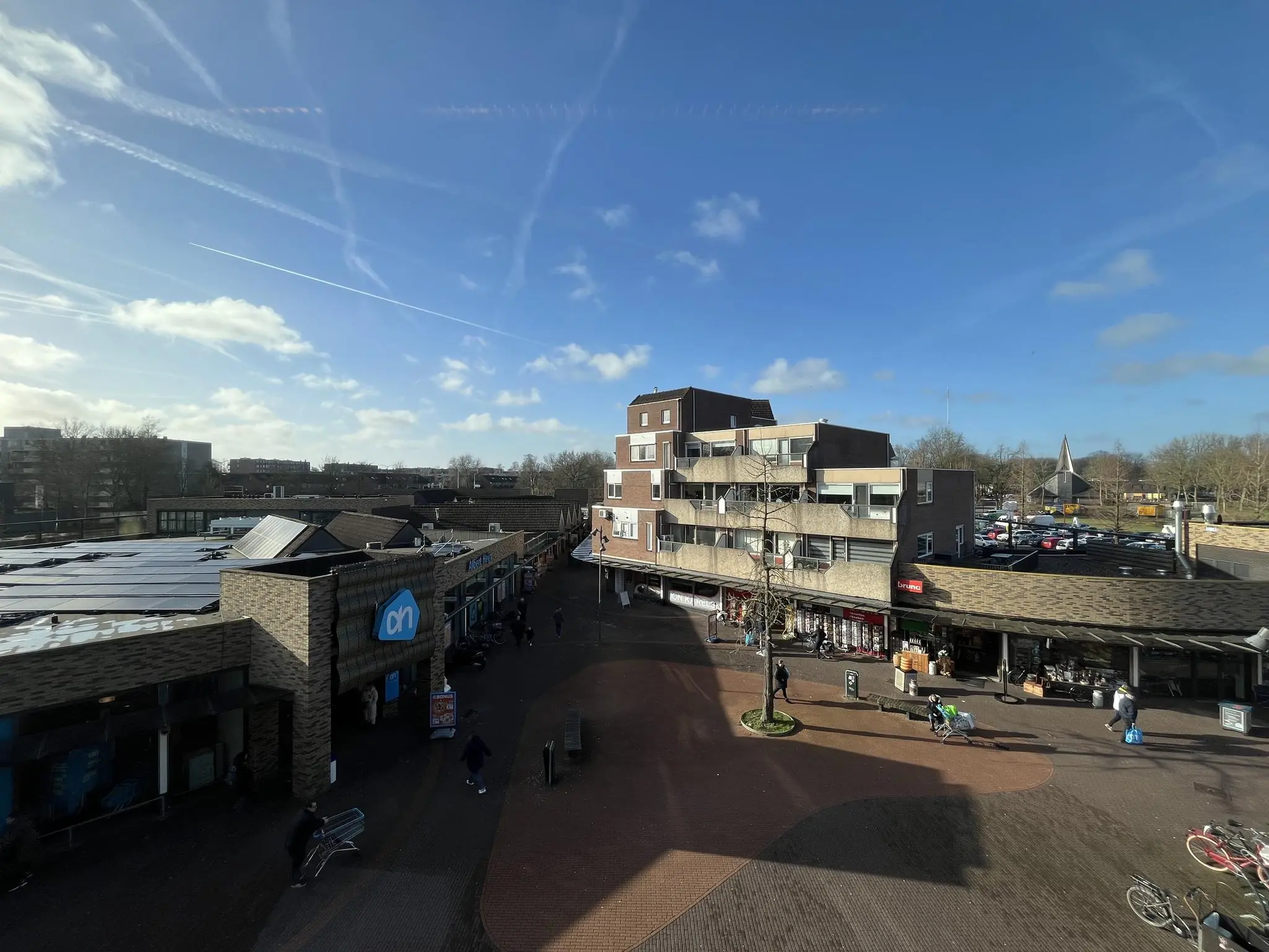 Winkelplein De Ratelaar in de zon met onder andere een Albert Heijn-filiaal en diverse andere winkels.