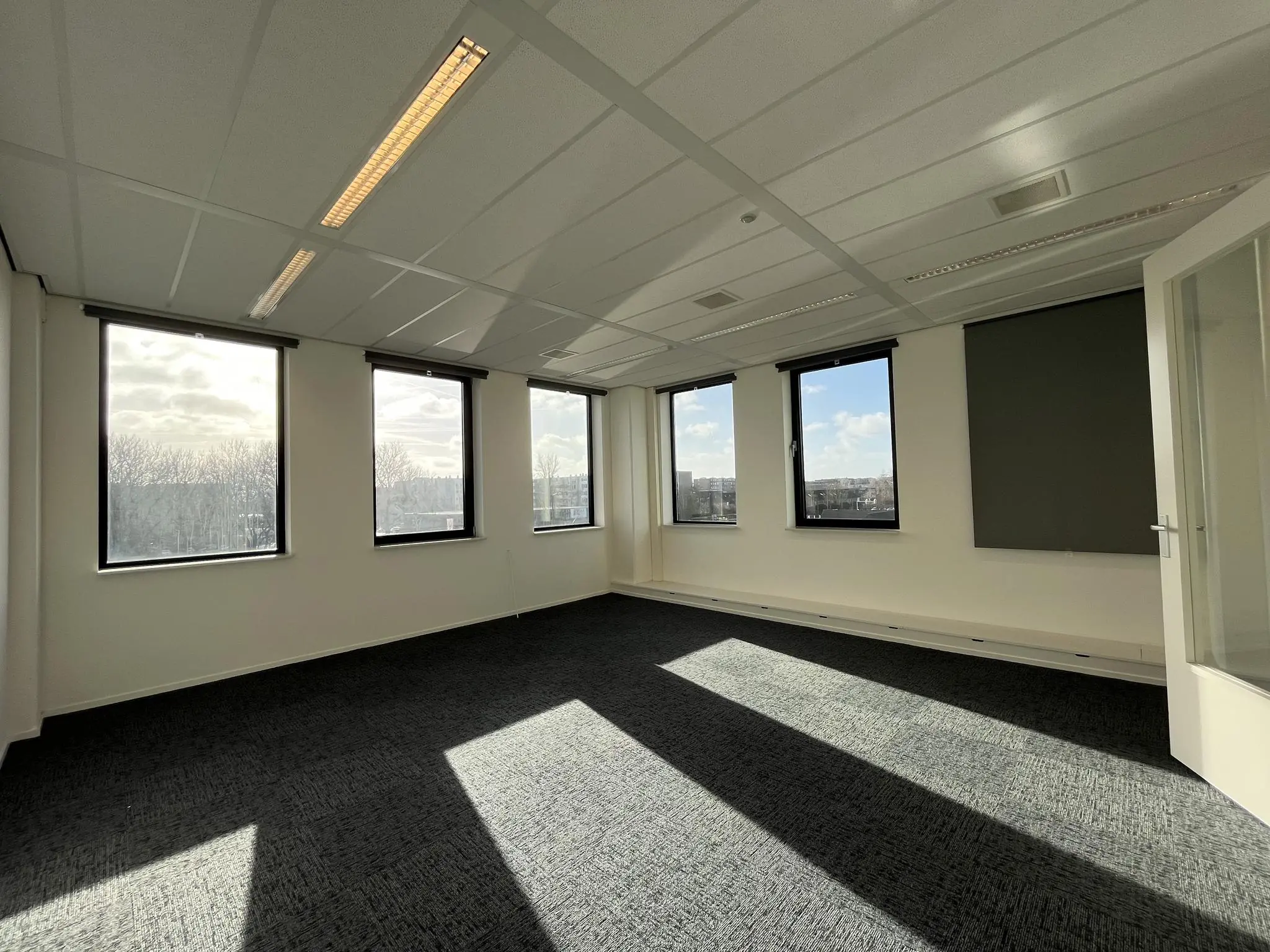 Licht en leeg kantoor in gebouw Ratelaar met grote ramen en verduisteringsgordijnen.