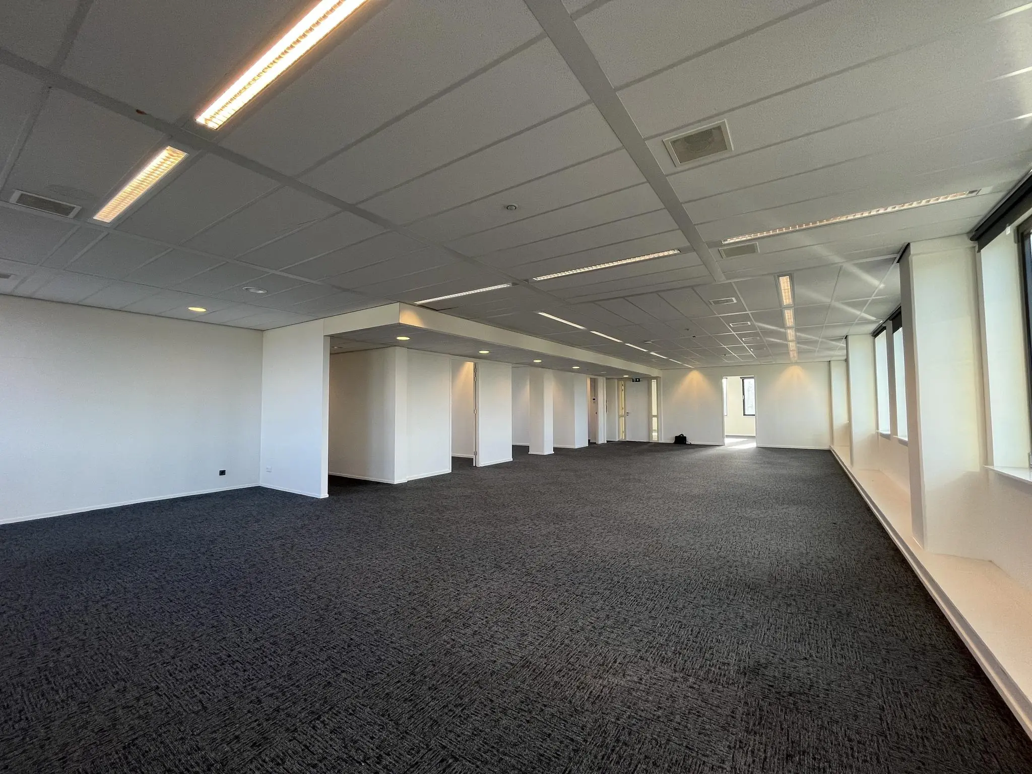 Lichte, ruime kantooretage in gebouw Ratelaar met tapijtvloer, systeemplafond en grote ramen.