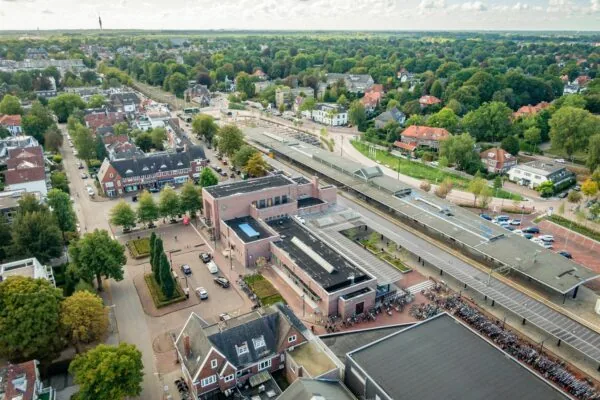 Luchtfoto van het Stationsplein met het treinstation van Hilversum en omliggende woonwijken.