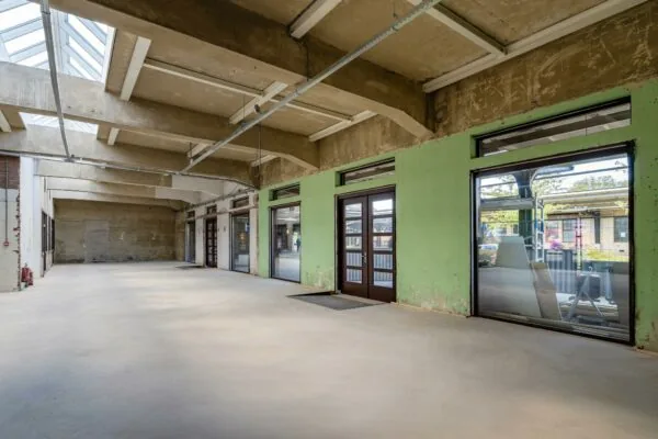 Leeg industrieel interieur met hoge plafonds, ramen en deuren aan Stationsplein.