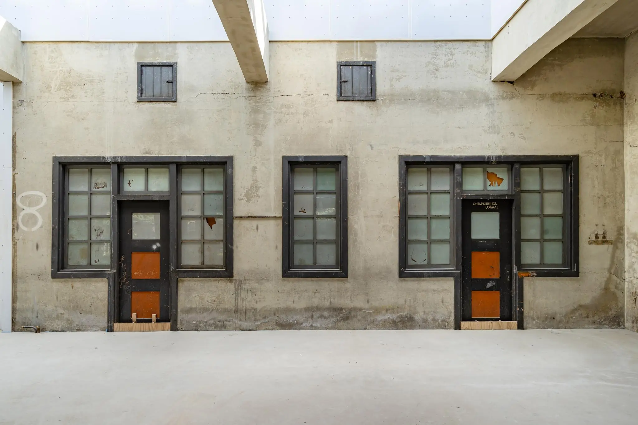 Vervallen gevel met twee deuren en oude ramen in het Stationsplein, met boven een deur het opschrift "Ontspanningslokaal".