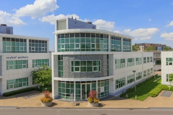 Modern kantoorgebouw van Vryhof Anchors aan het Rhijnspoor, met glazen gevel en betegelde entree.