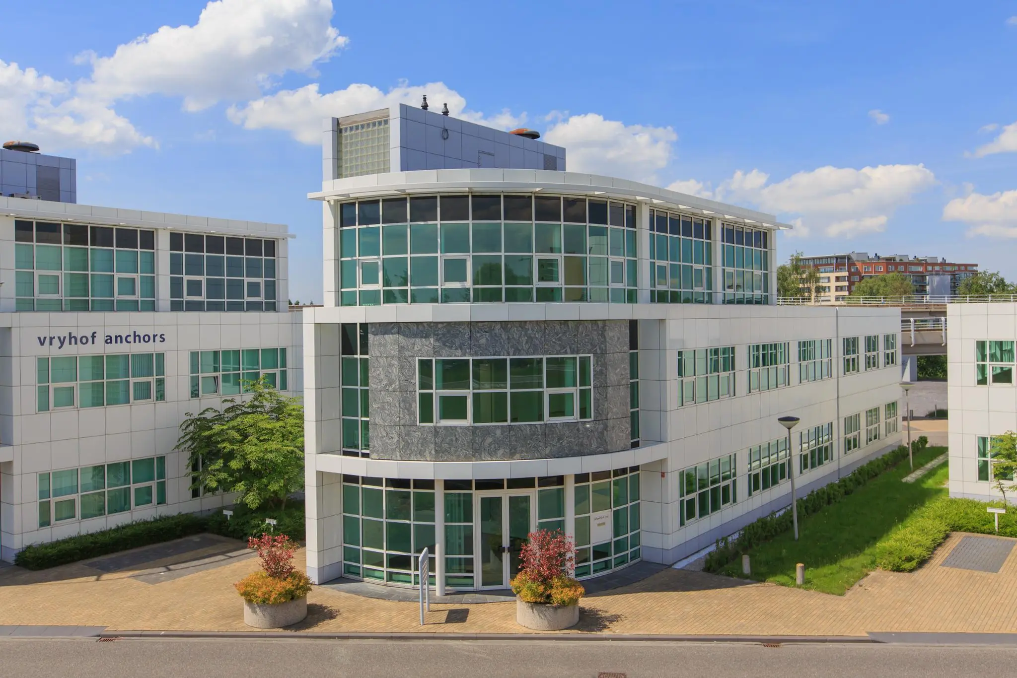 Modern kantoorgebouw van Vryhof Anchors aan het Rhijnspoor, met glazen gevel en betegelde entree.