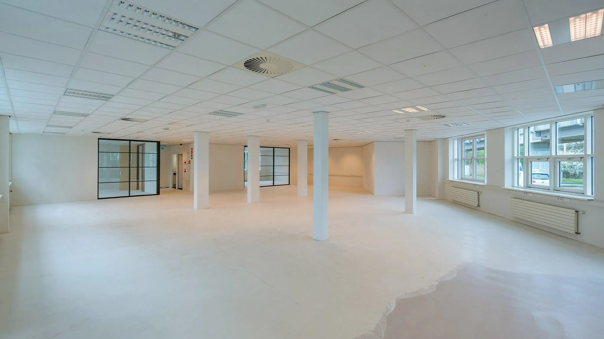 Licht en modern kantoorpand aan het Rhijnspoor met glazen wanden en grote ramen.