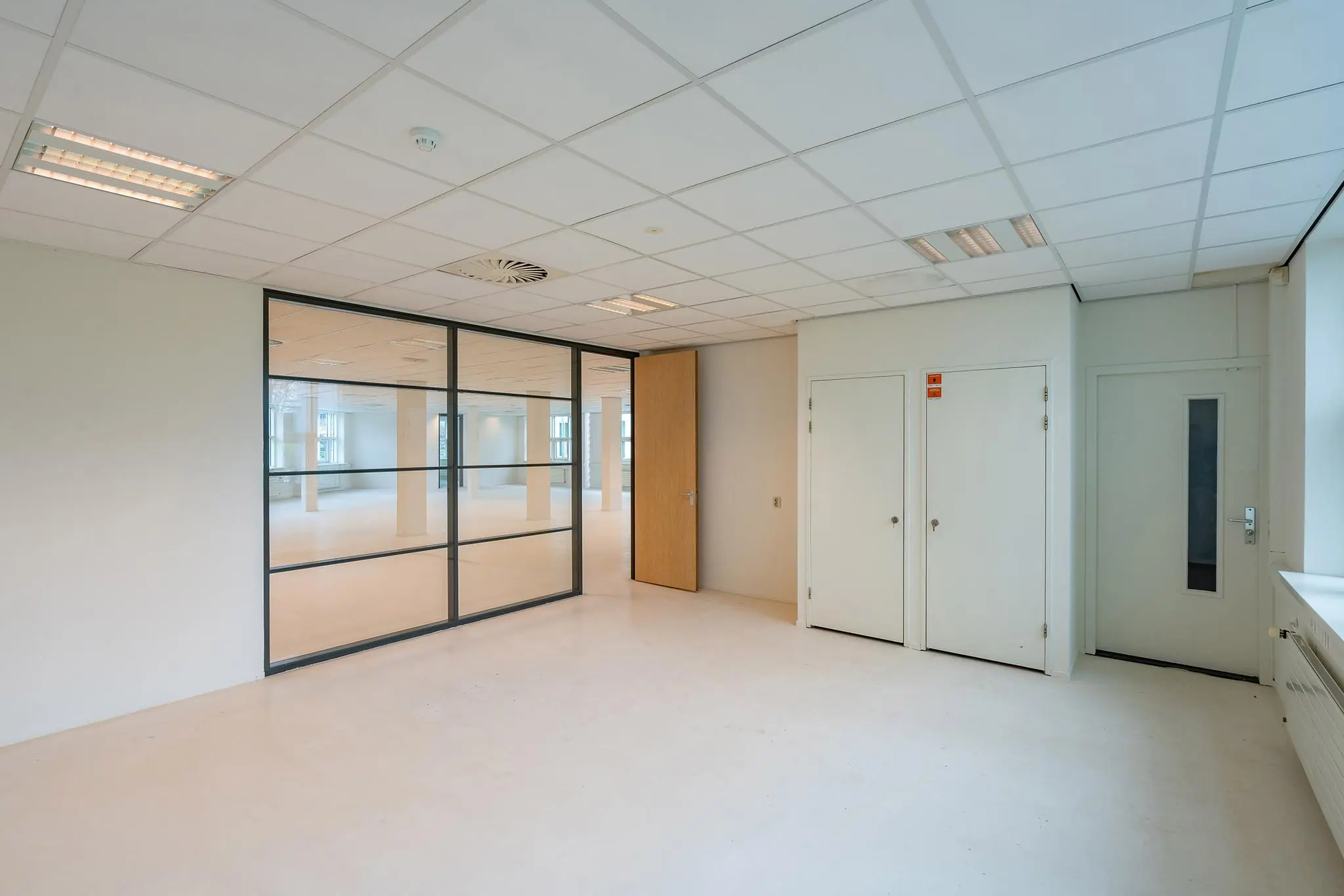 Licht en modern kantoorinterieur aan het Rhijnspoor met glazen tussenwand en witte deuren.