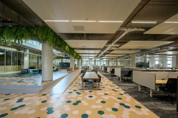 Moderne en open kantoorruimte aan de Coolsingel met kleurrijke geometrische vloerpatronen, werkplekken en groene plafonddecoratie.