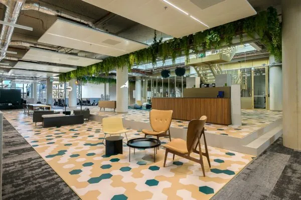 Moderne, open kantoorruimte aan de Coolsingel met kleurrijke geometrische vloer, zithoek en hangende planten.